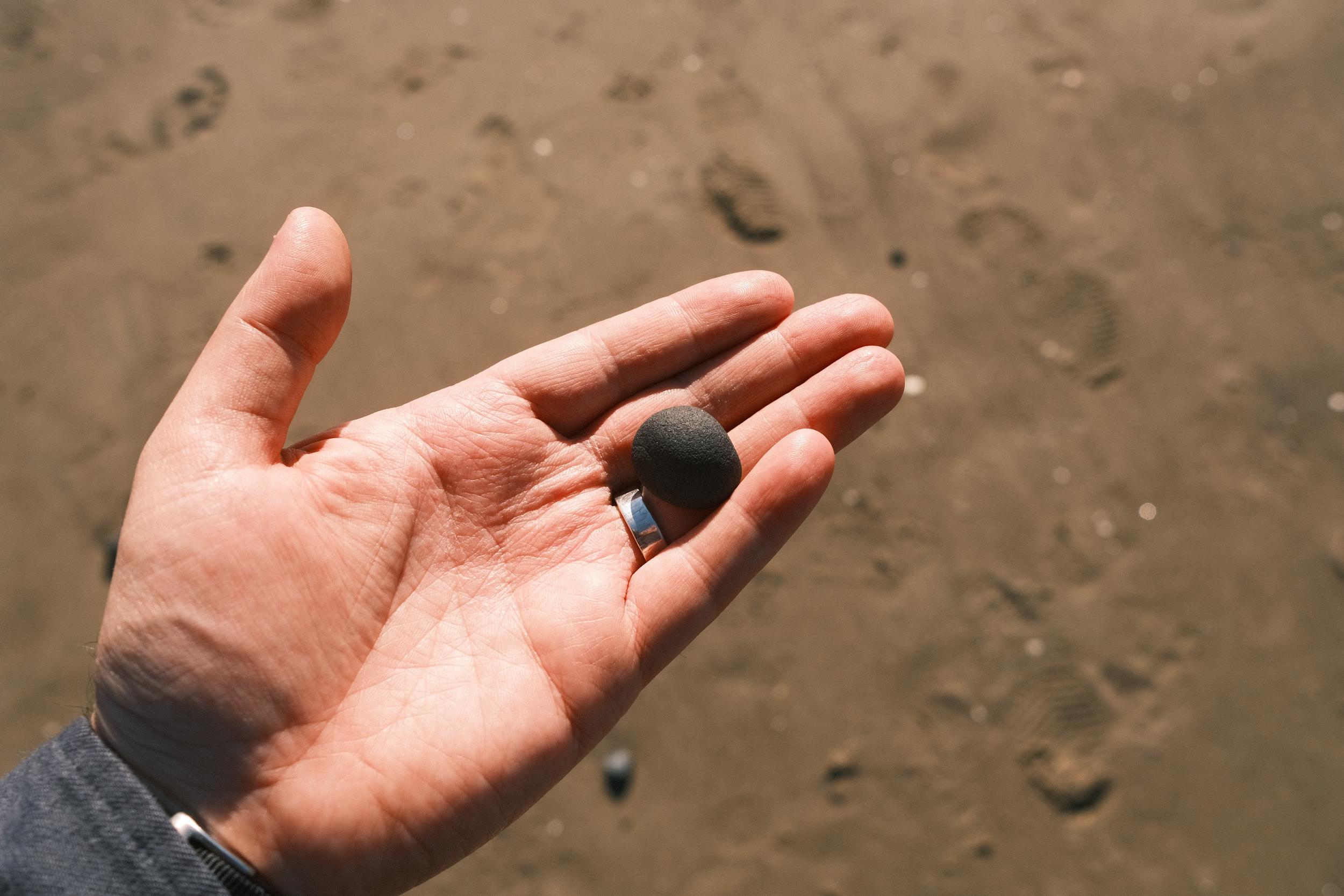 A small black stone being held in the palm of a hand